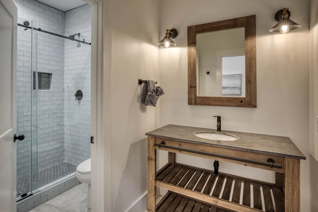A bathroom with a sink , mirror and walk in shower.