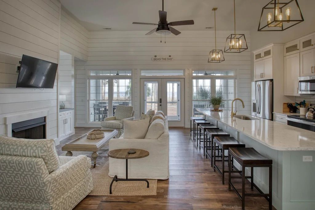 A living room and kitchen in a house with a ceiling fan.