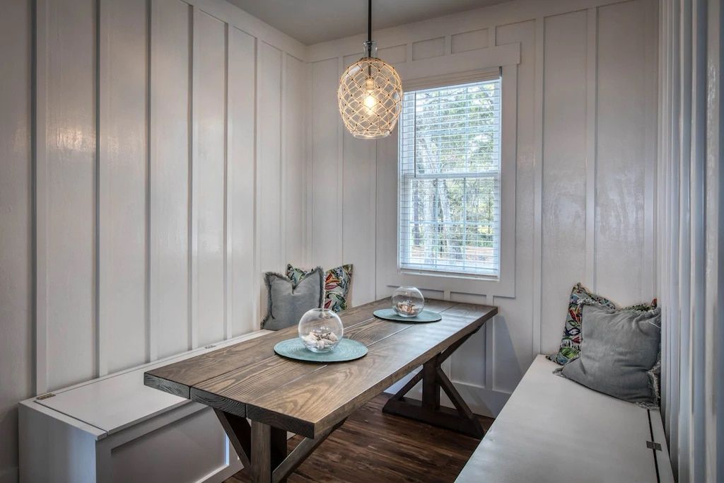 A dining room with a table and a bench in front of a window.