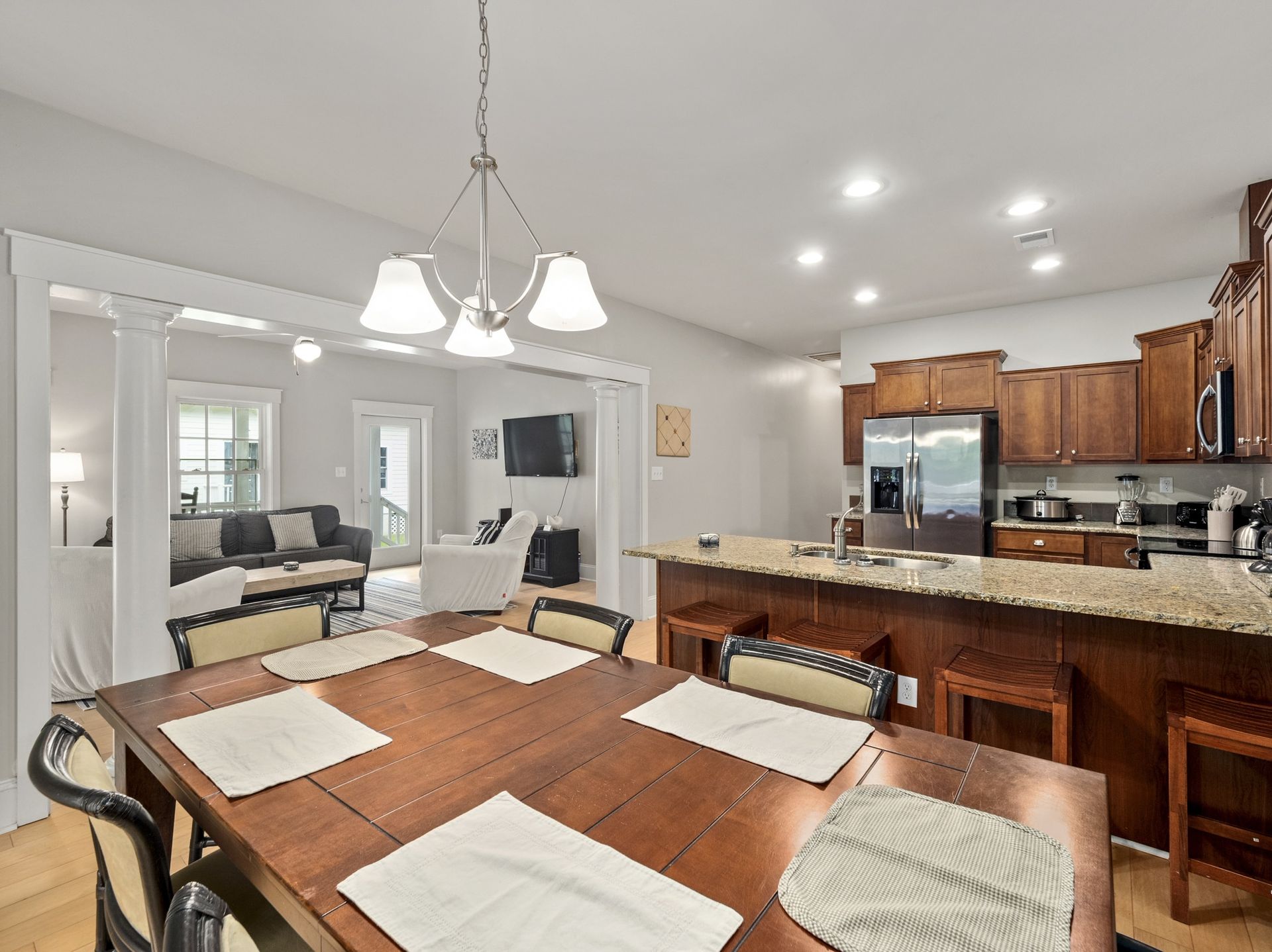 A dining room table and chairs in a kitchen with a stainless steel refrigerator.