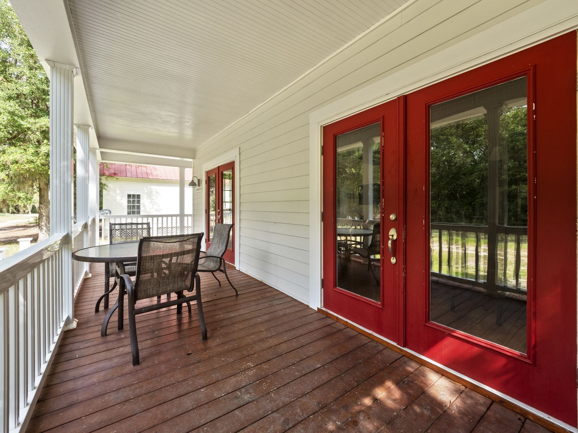 A porch with a table and chairs and red doors