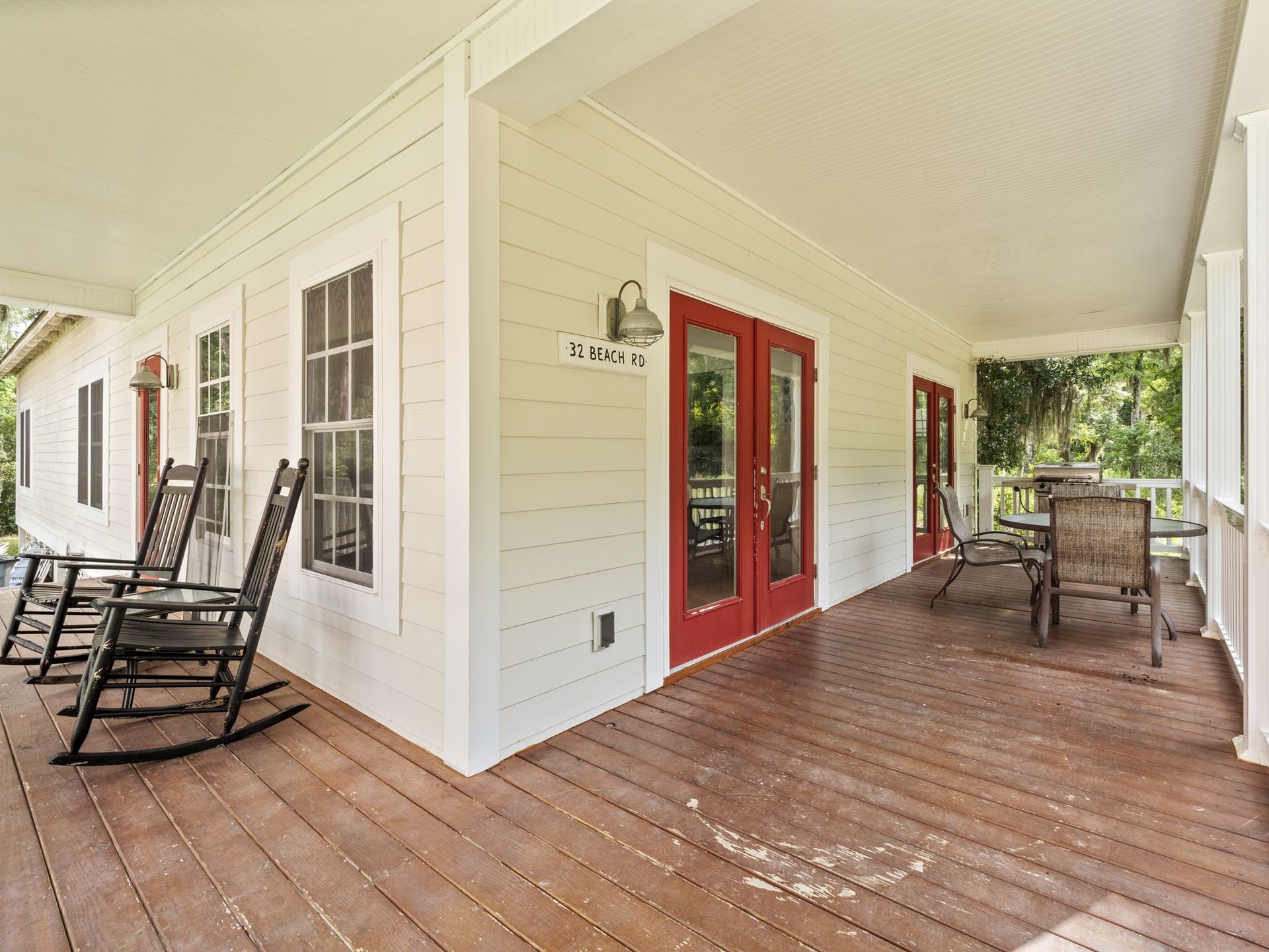 A porch with rocking chairs and a table and chairs on it.