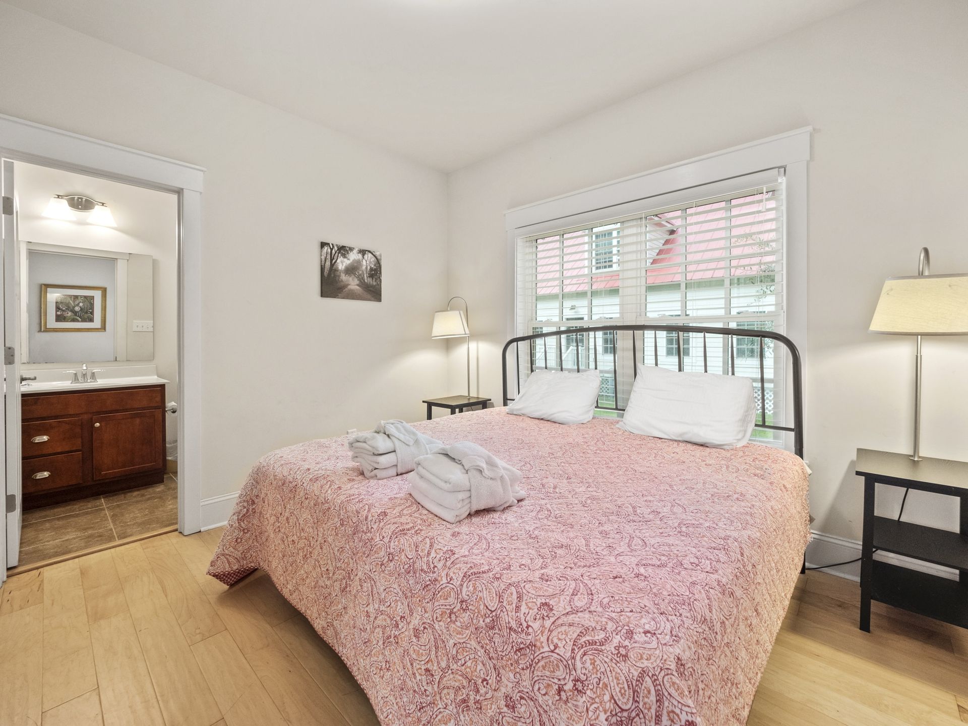 A bedroom with a king size bed , nightstand , lamp and window.