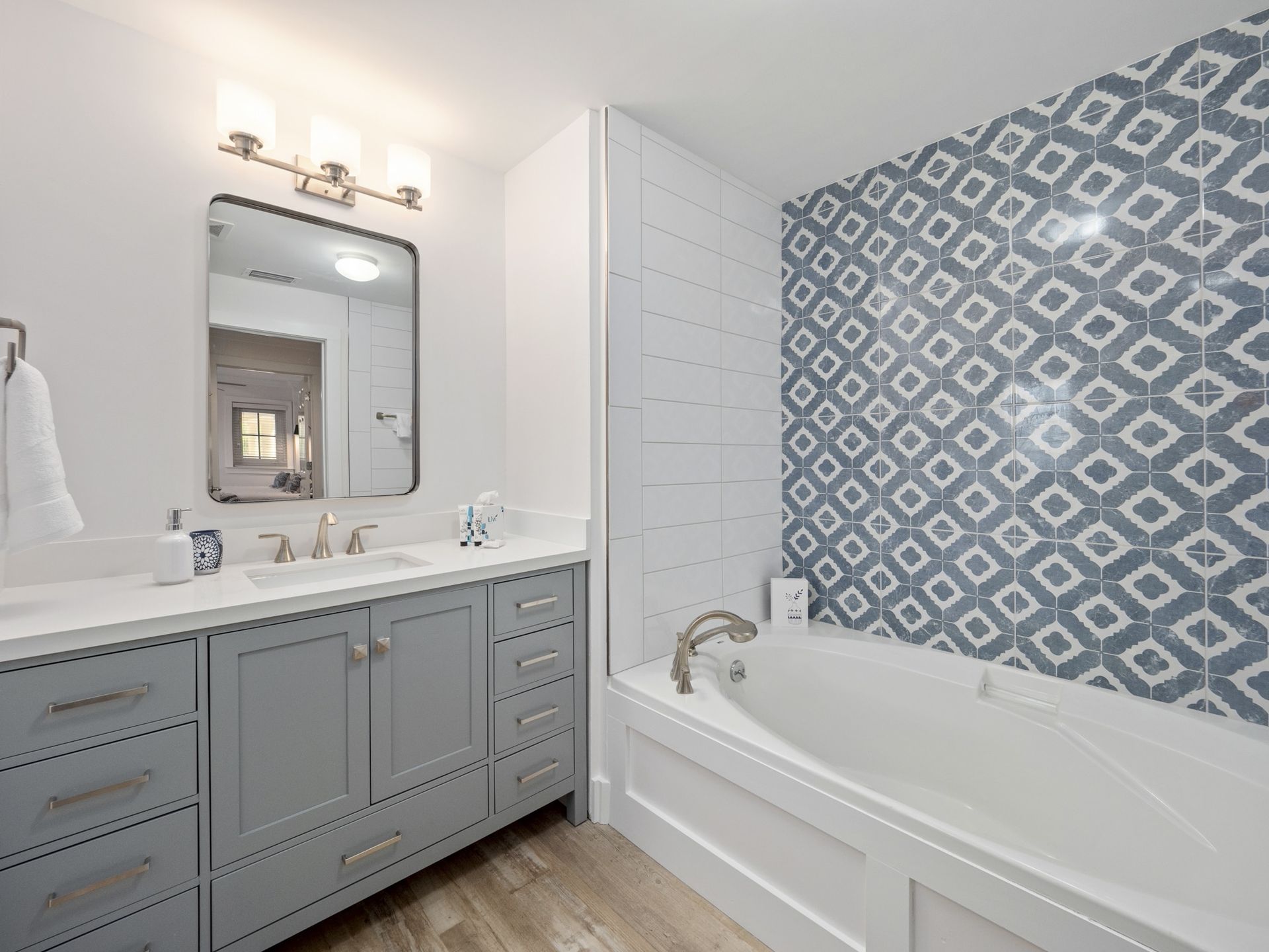 A bathroom with a bathtub , sink and mirror.