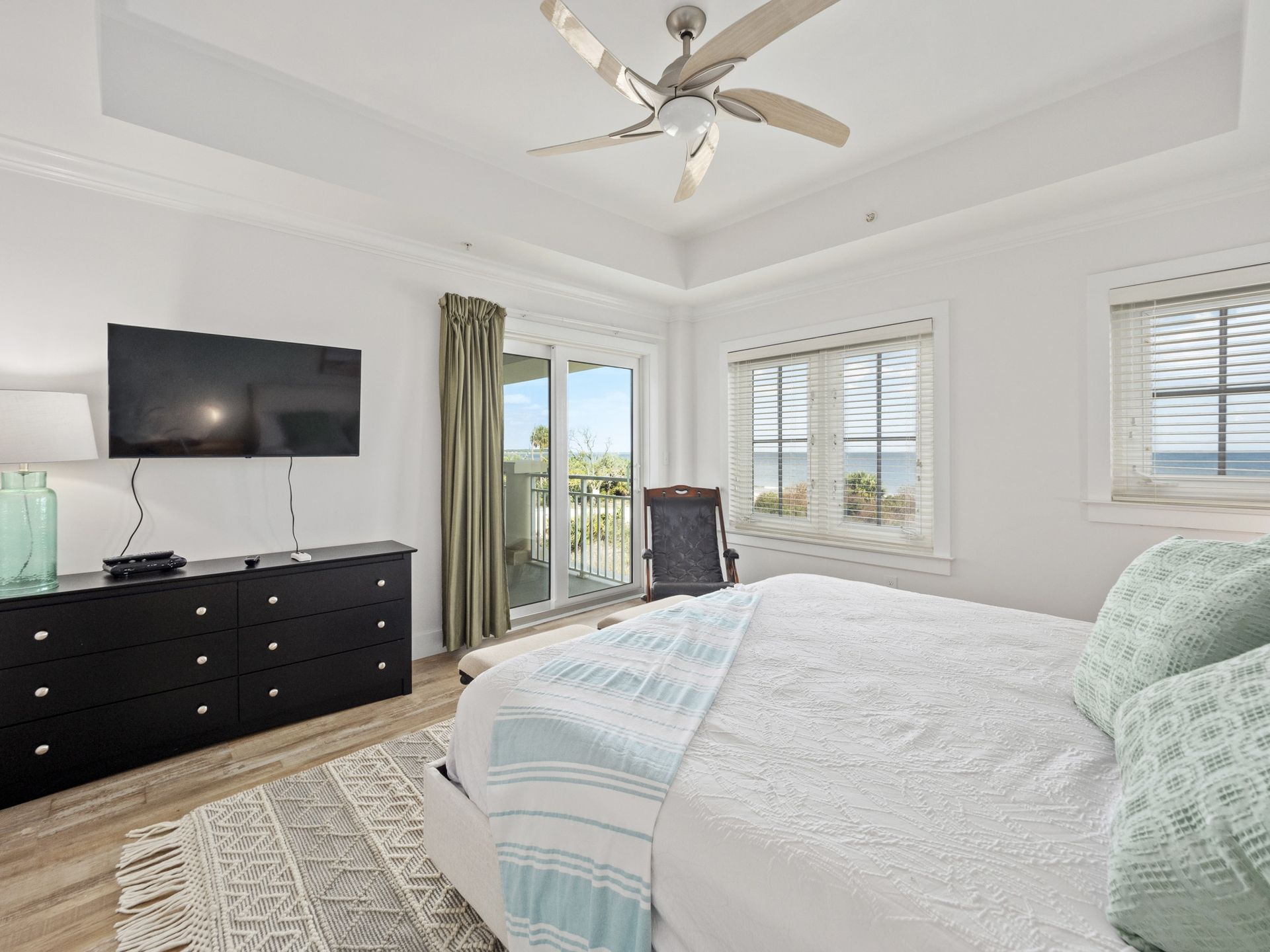 A bedroom with a bed , dresser , television and ceiling fan.