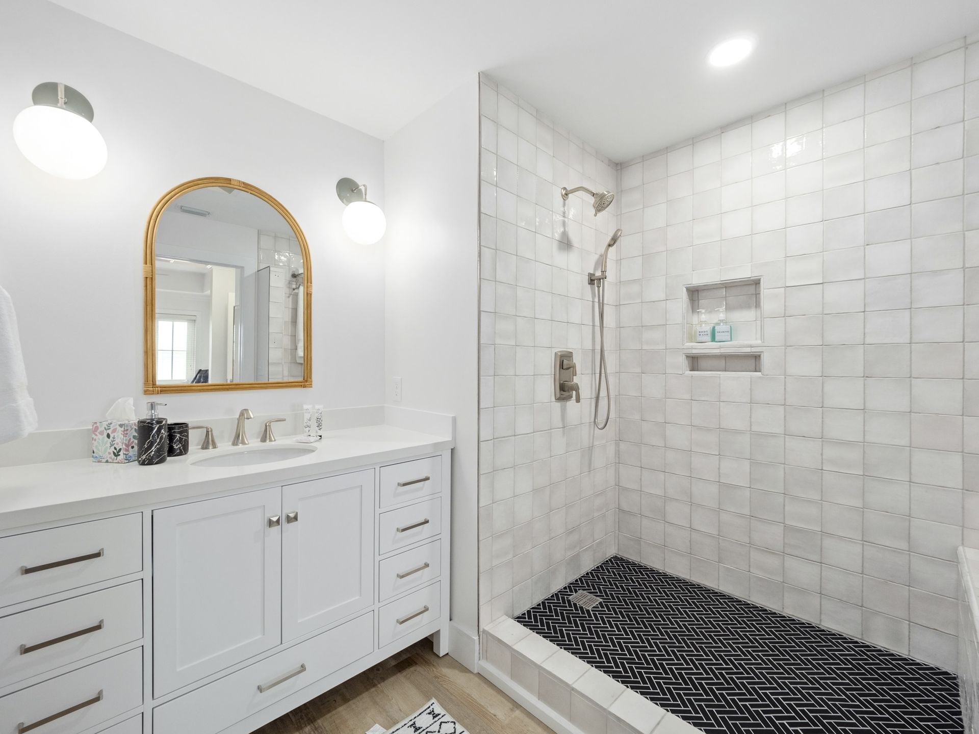 A bathroom with a walk in shower , sink and mirror.