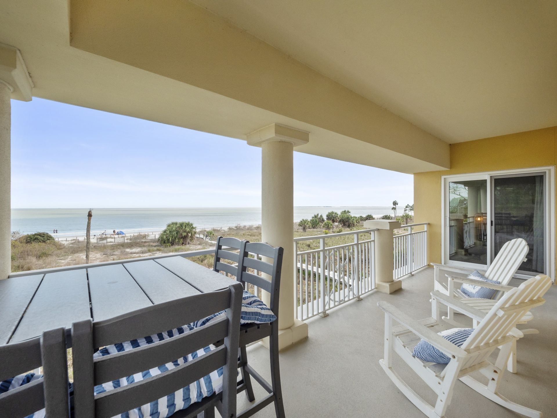A balcony with a table and chairs overlooking the ocean.