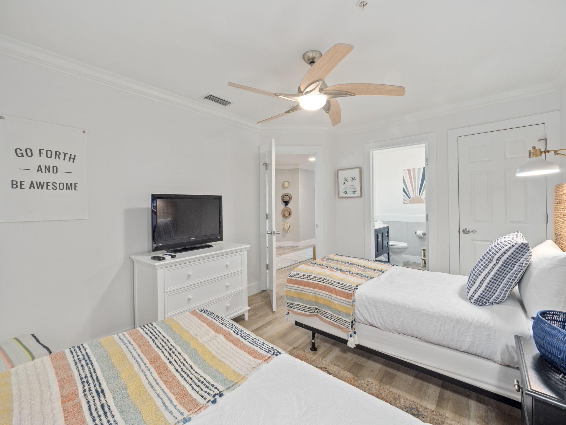 A bedroom with two beds , a television and a ceiling fan.