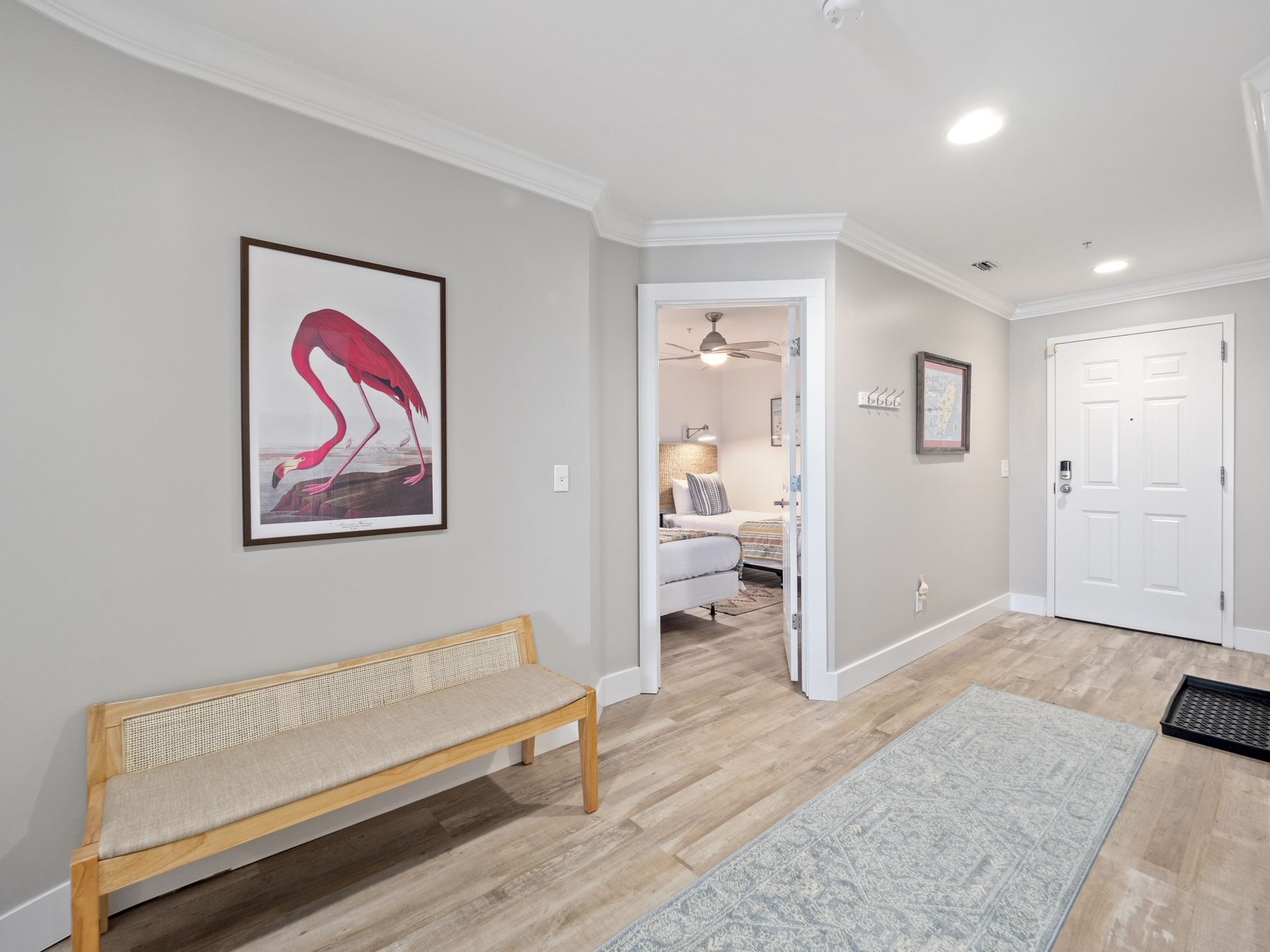 A hallway with a bench and a picture of a flamingo on the wall.