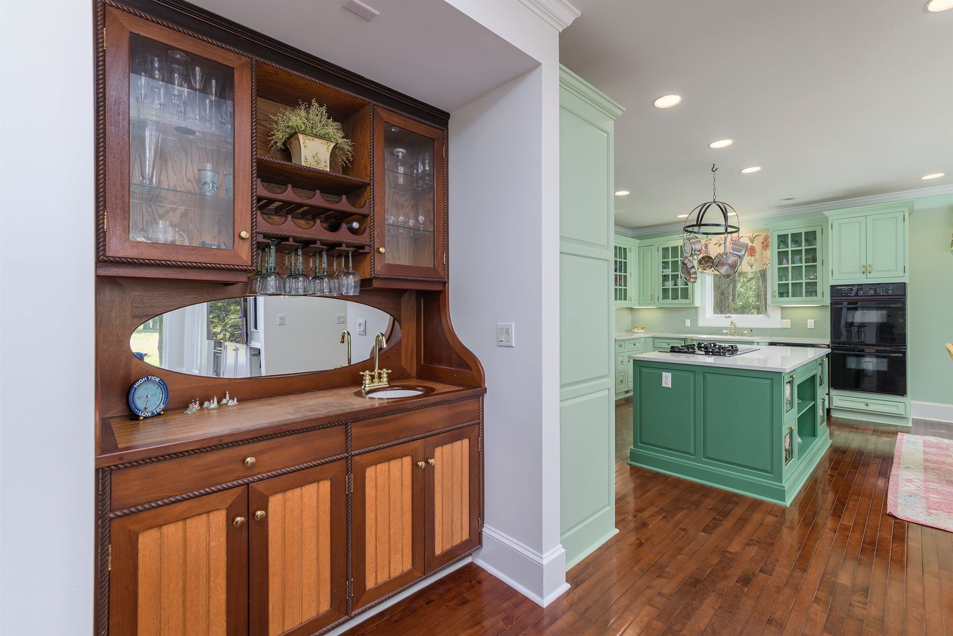 A kitchen with green cabinets and a buffet with a mirror on top of it.