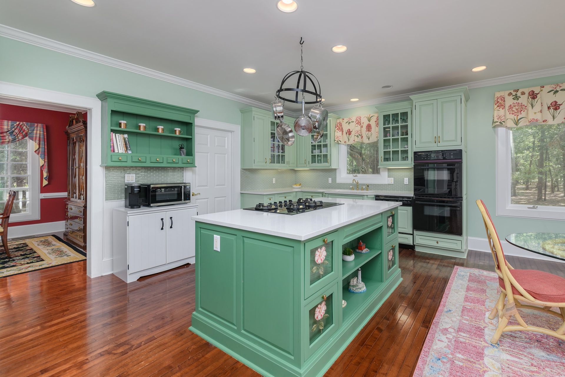 A kitchen with green cabinets and a large island in the middle.