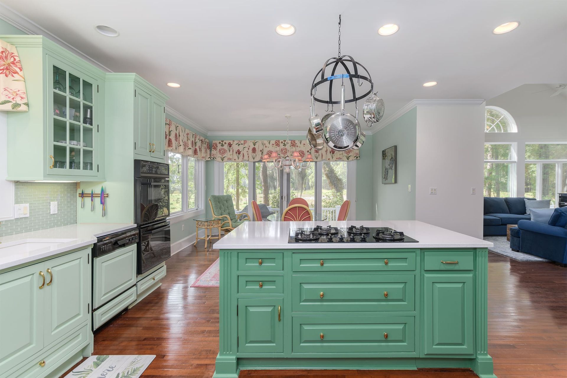 A kitchen with green cabinets and a large island in the middle.
