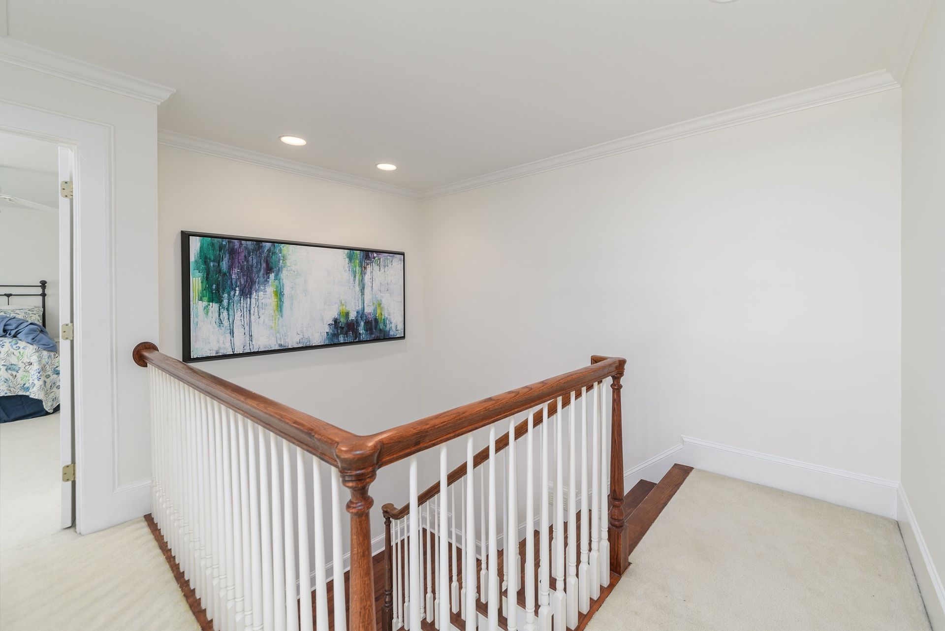 A staircase with a wooden railing and a painting on the wall.