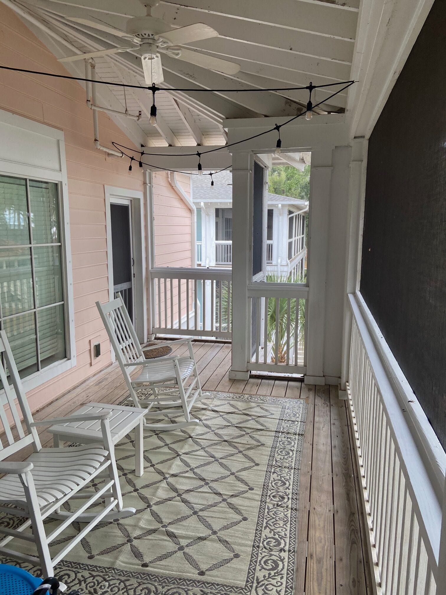 A screened in porch with rocking chairs and a rug.