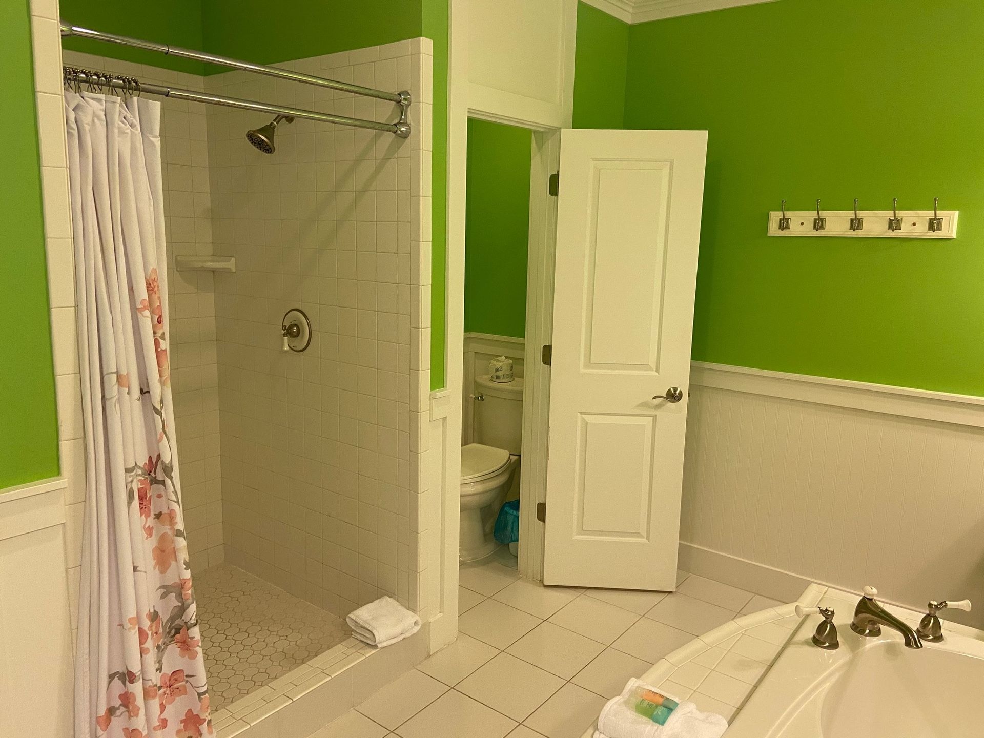 A bathroom with green walls , a tub , a toilet and a shower.