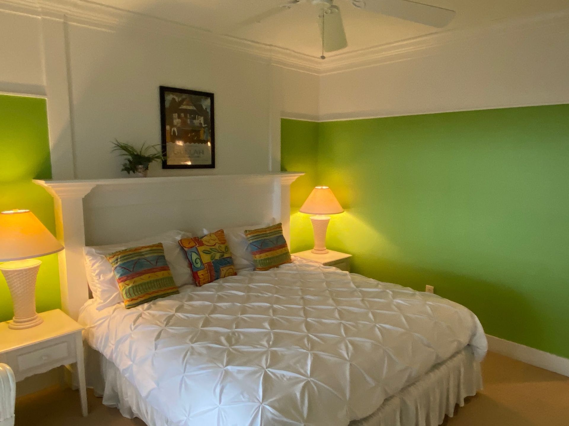 A bedroom with a bed , lamps and green walls.