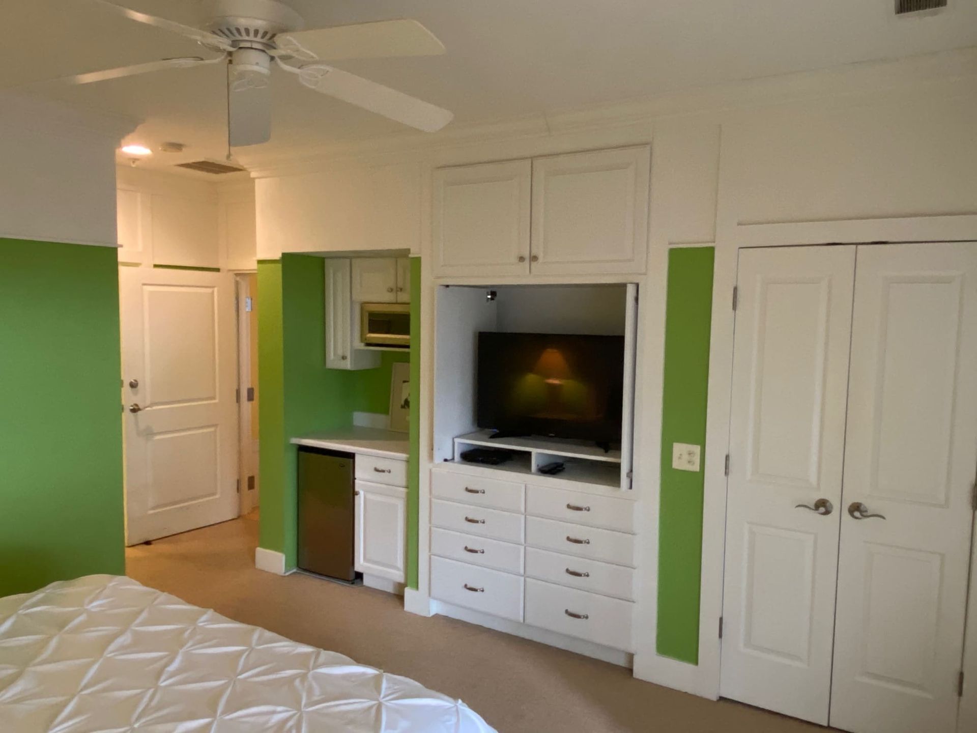 A bedroom with a ceiling fan and a flat screen tv
