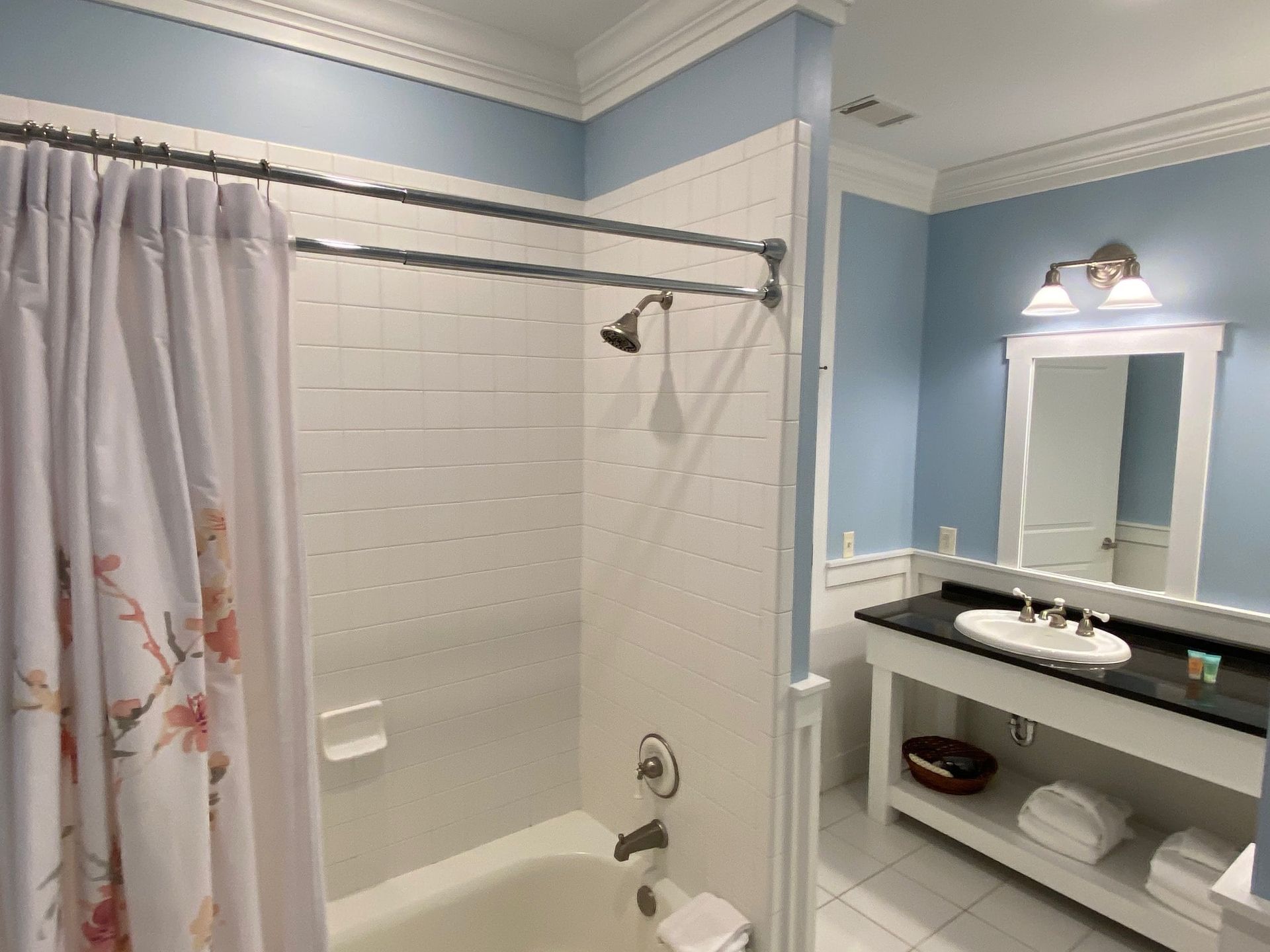 A bathroom with a tub , sink , mirror and shower curtain