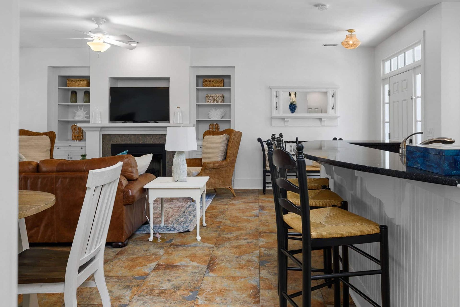 A living room with a couch , chairs , a television and a bar.