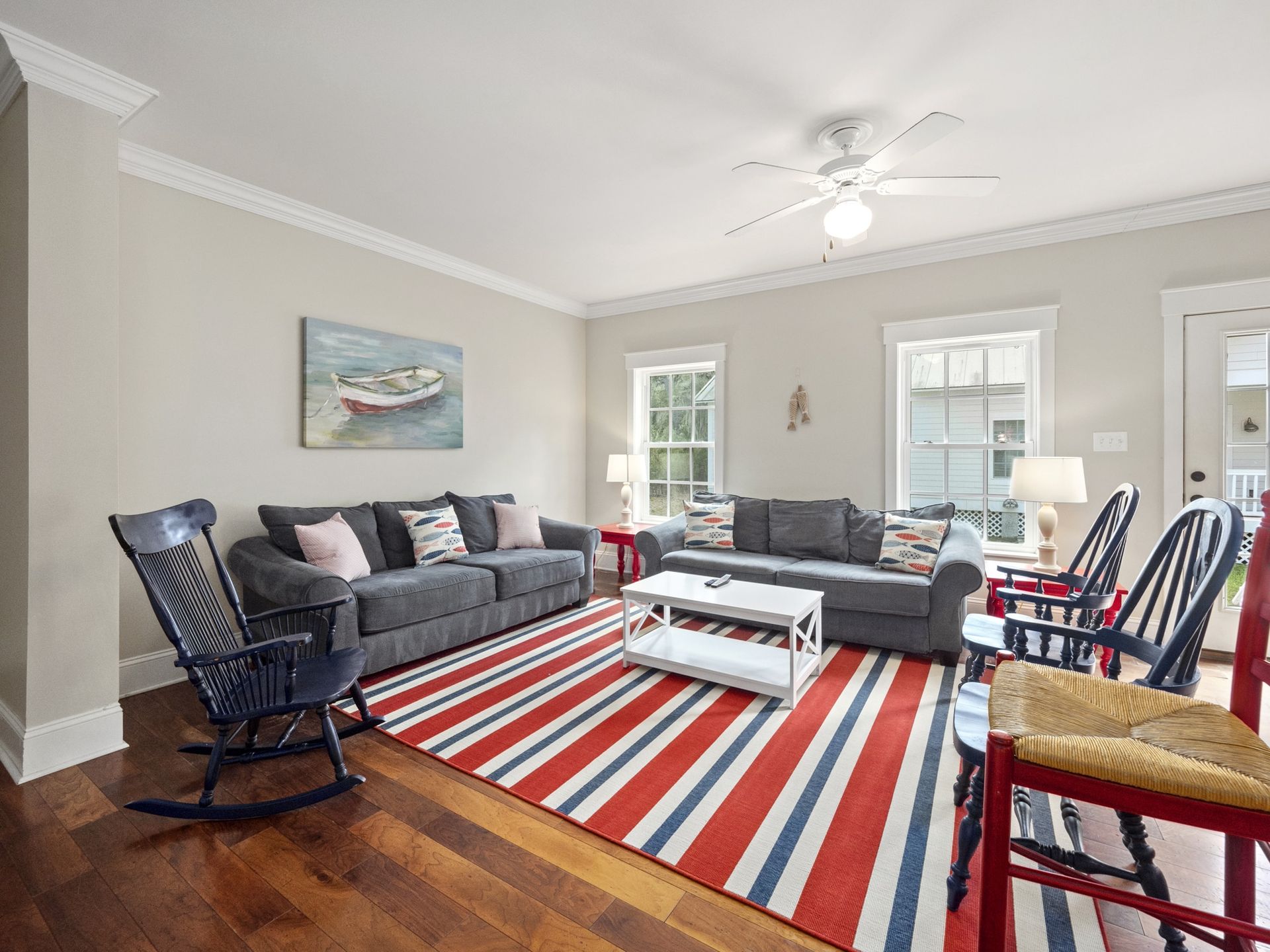 A living room with a couch , chairs , a rug and a ceiling fan.