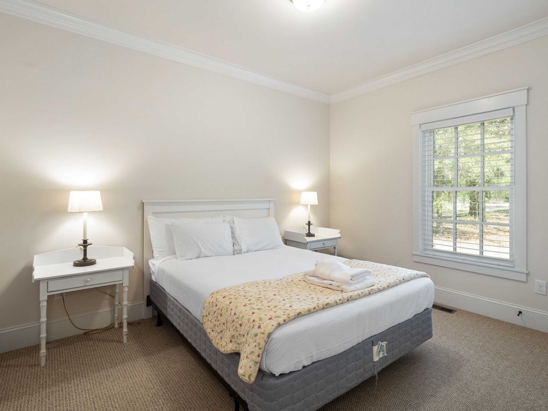 A bedroom with a bed , two nightstands and a window.