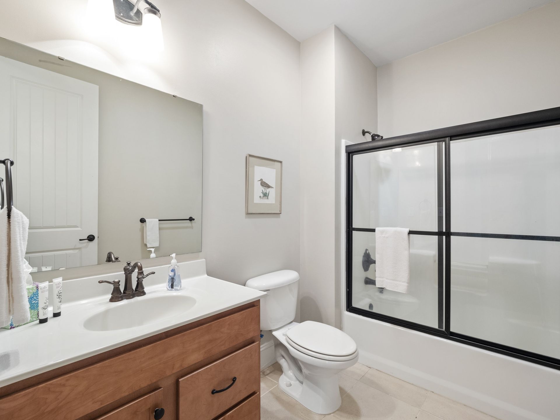 A bathroom with a toilet , sink , mirror and bathtub.