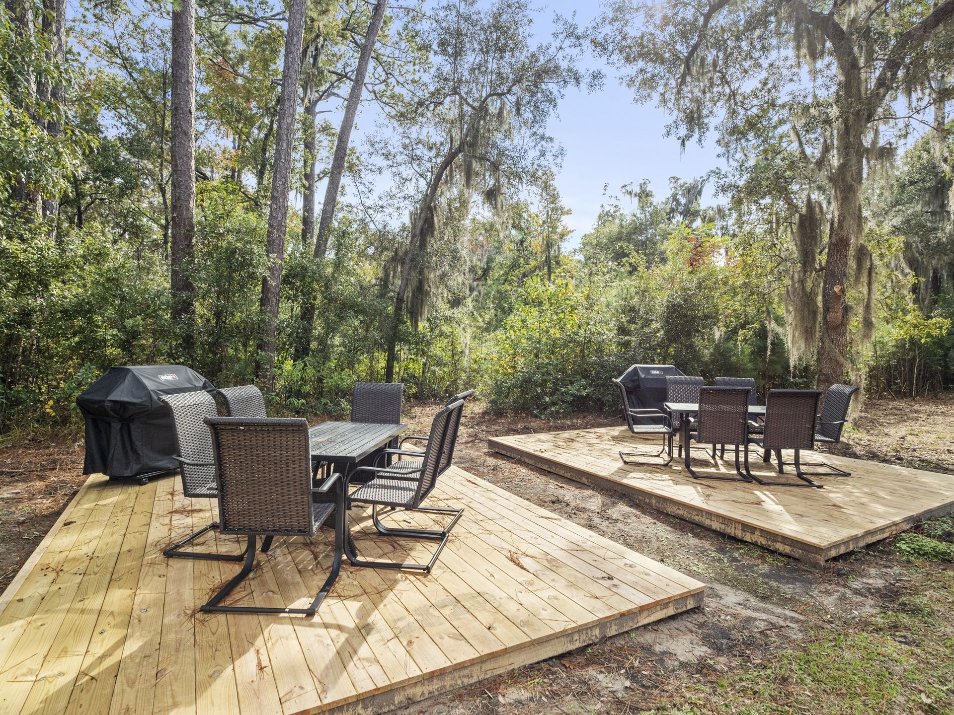 A wooden deck with a table and chairs and a grill.
