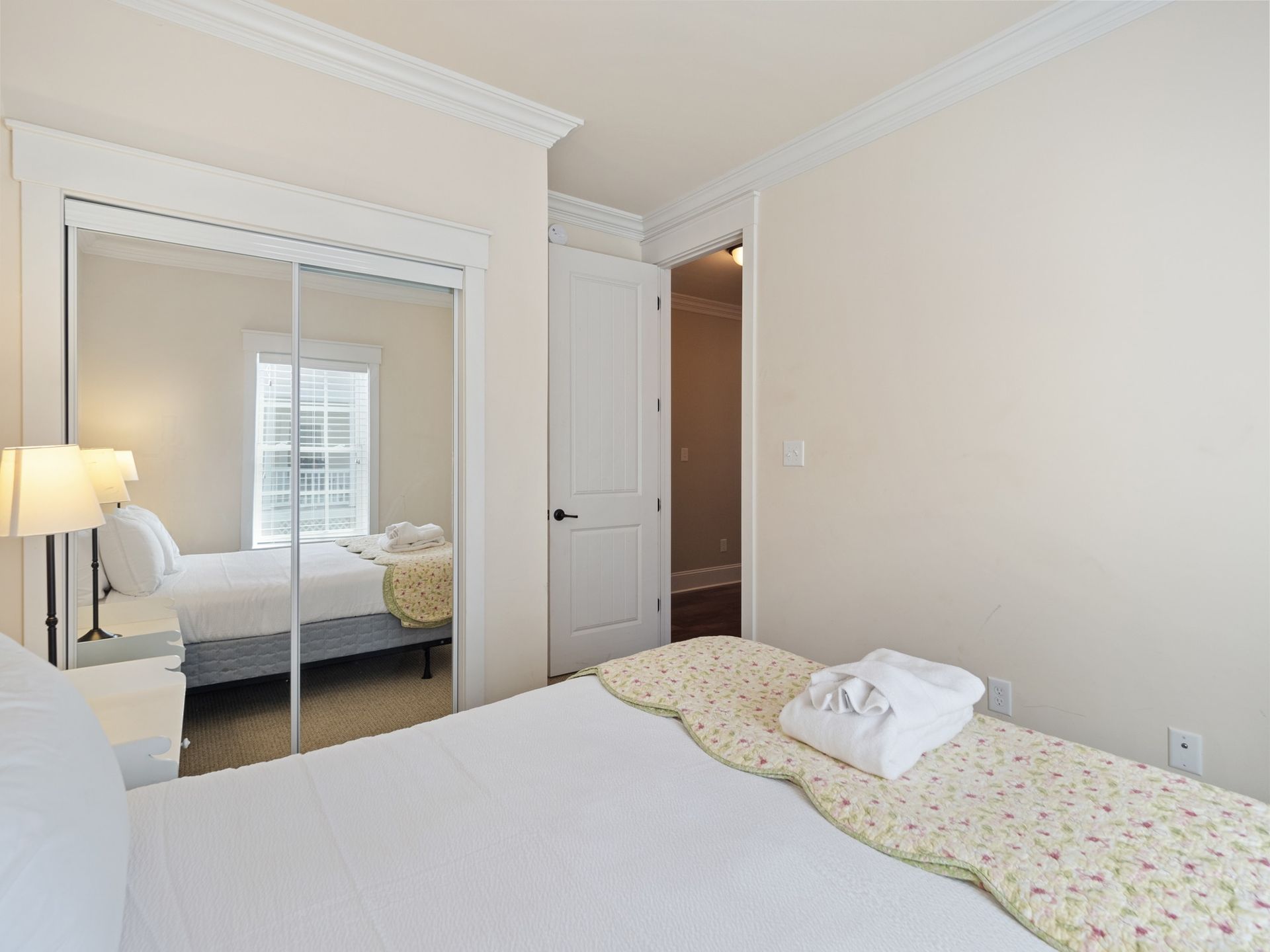 A bedroom with a king size bed and a mirrored closet.