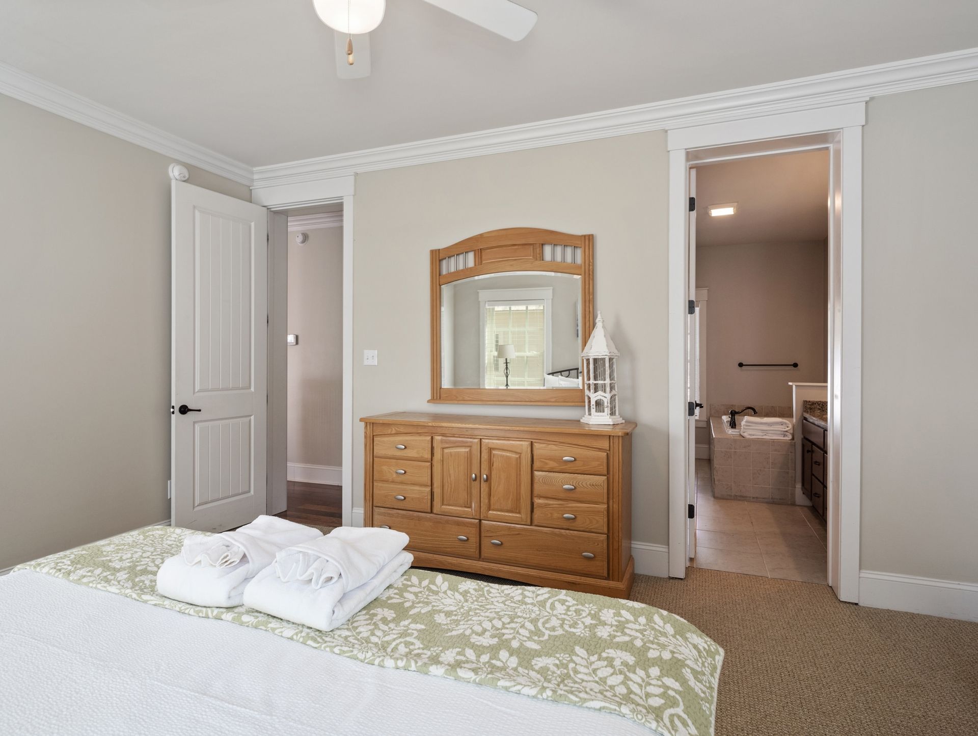 A bedroom with a bed , dresser , mirror and ceiling fan.