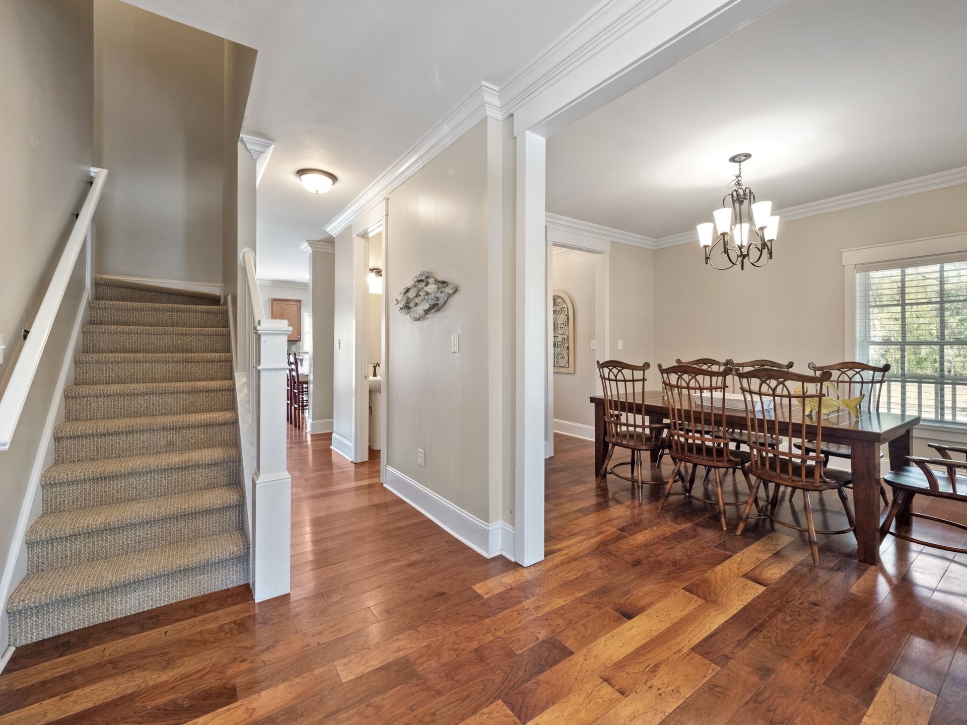 A dining room with a table and chairs and stairs leading to the second floor.