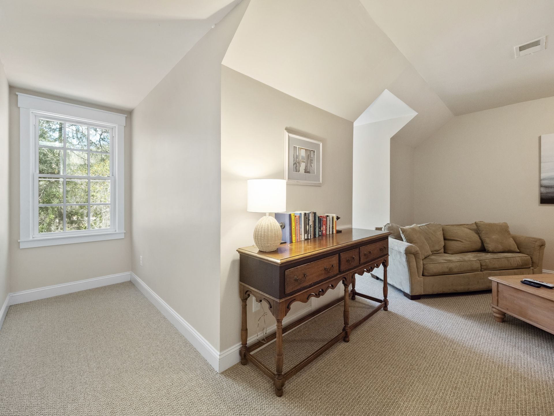 A living room with a couch , table , lamp and window.