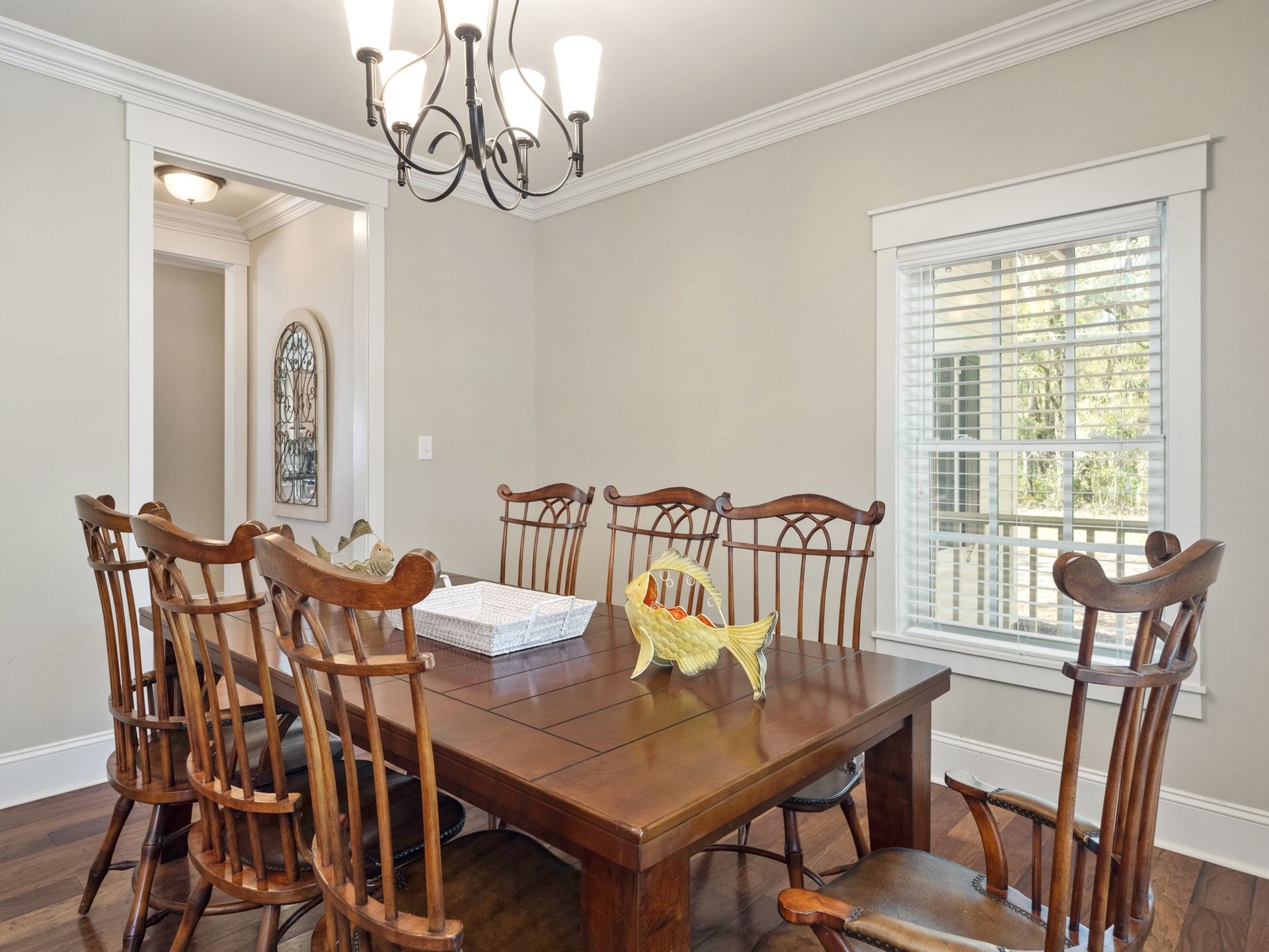 A dining room with a wooden table and chairs and a chandelier.