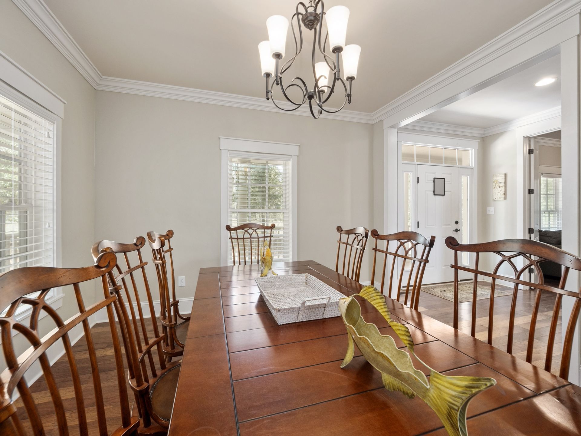 A dining room with a long table and chairs and a chandelier.