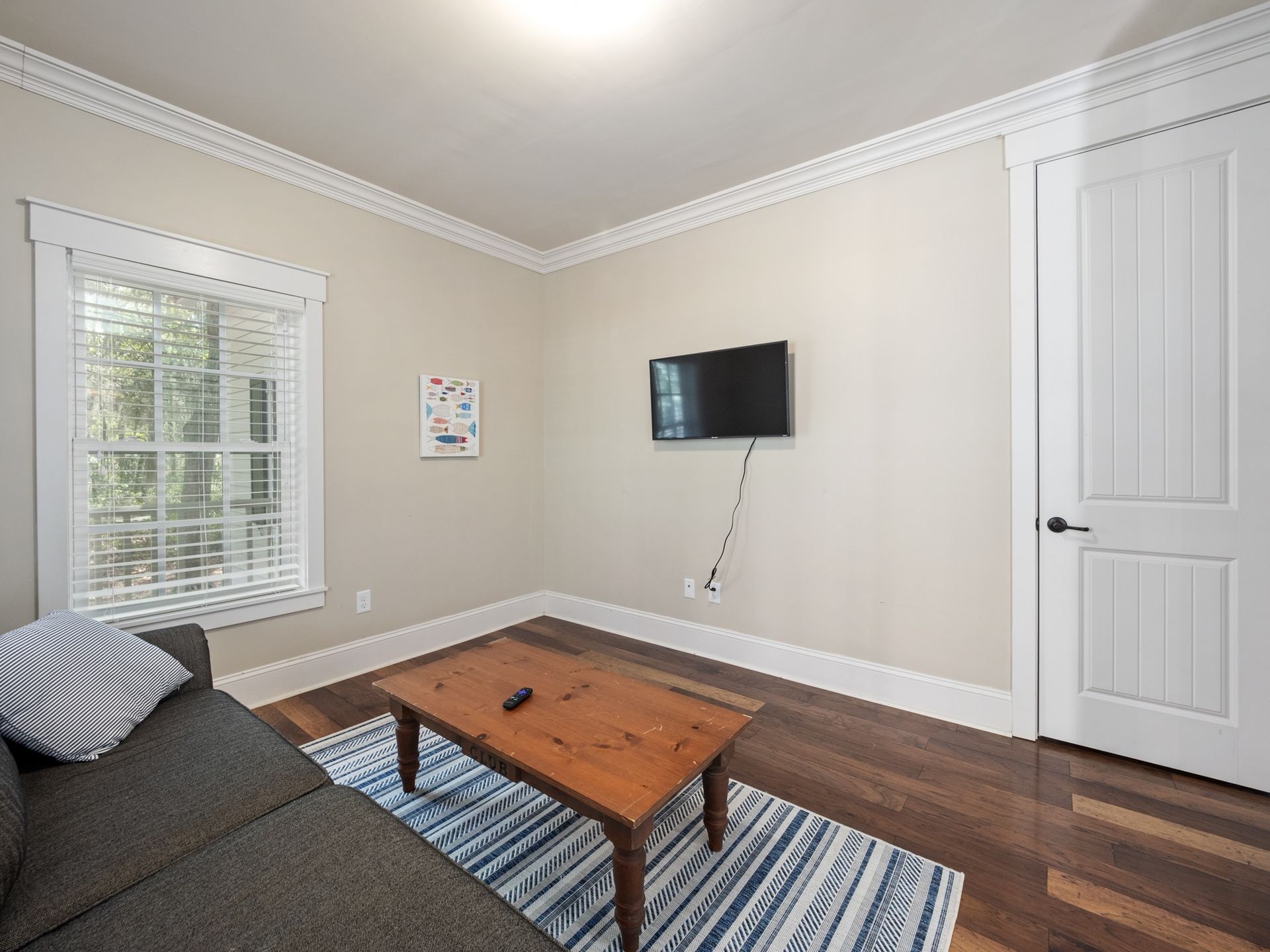A living room with a couch , coffee table , and television on the wall.
