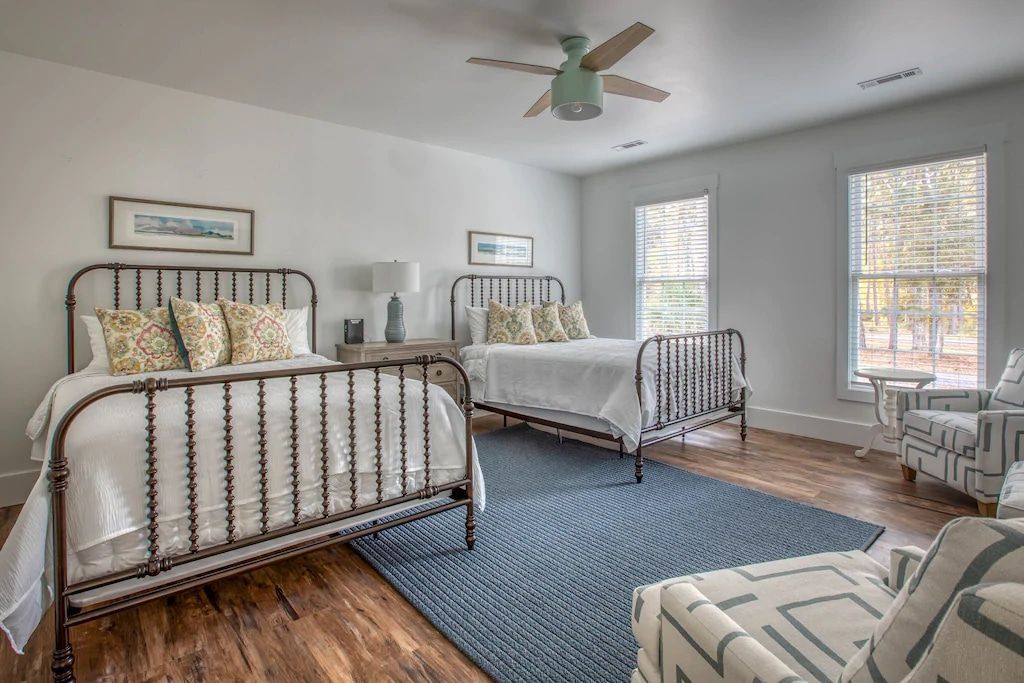 A bedroom with two beds , a chair , and a ceiling fan.
