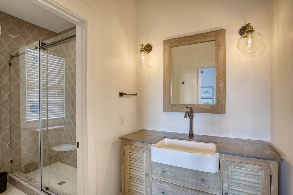 A bathroom with a sink , mirror and shower.
