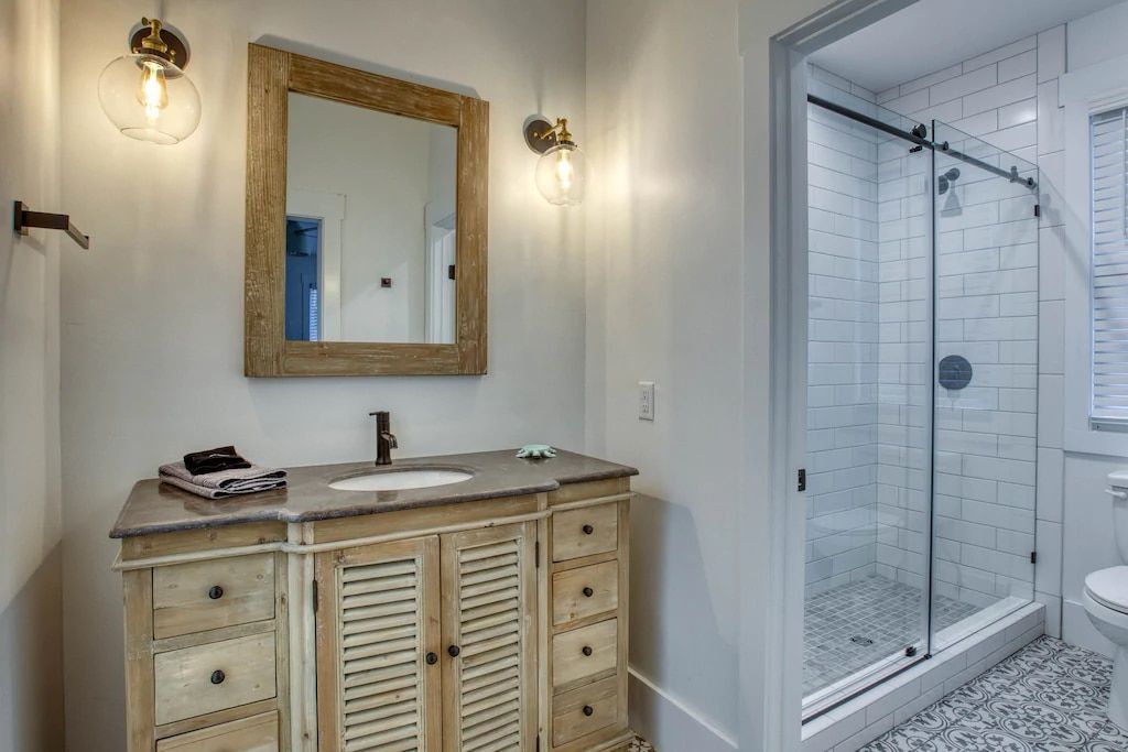 A bathroom with a sink , mirror , and walk in shower.