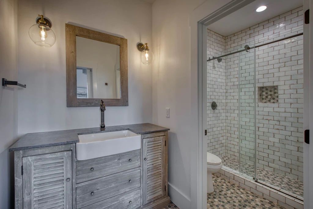 A bathroom with a sink , mirror and walk in shower.
