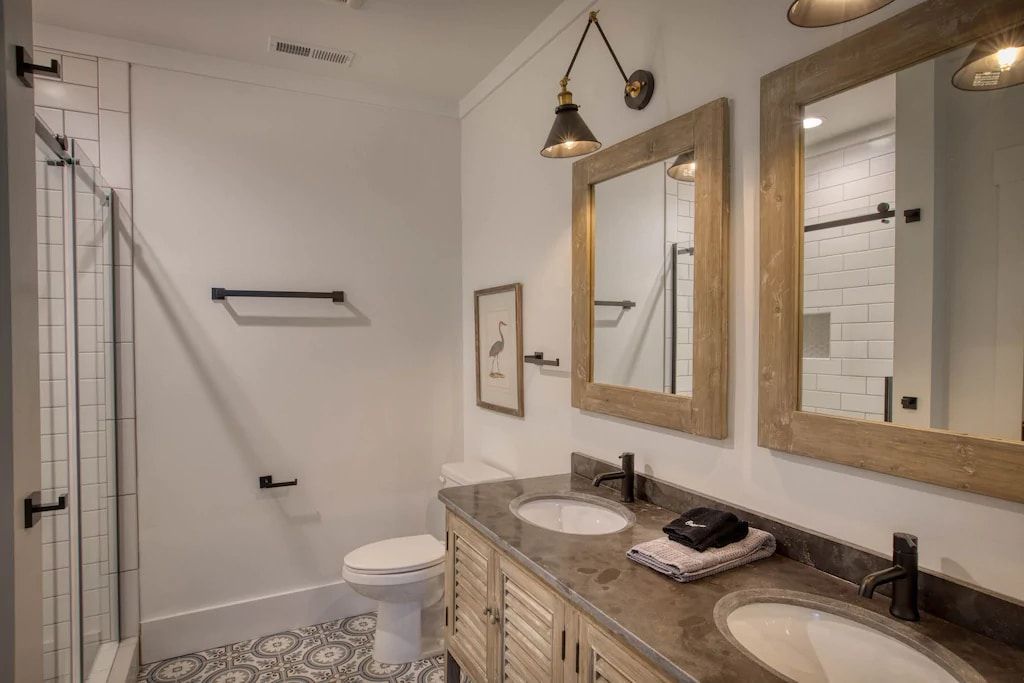 A bathroom with two sinks , a toilet , and a shower.