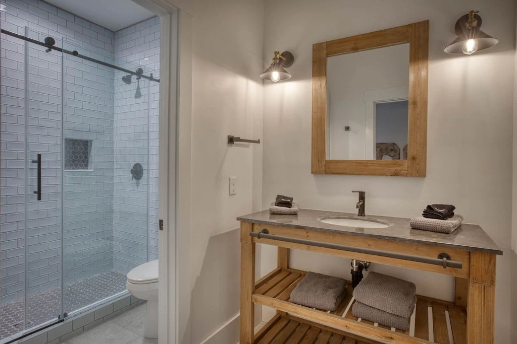 A bathroom with a sink , mirror and shower.