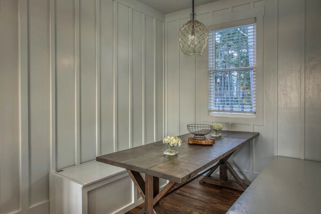 A dining room with a table and bench in front of a window.