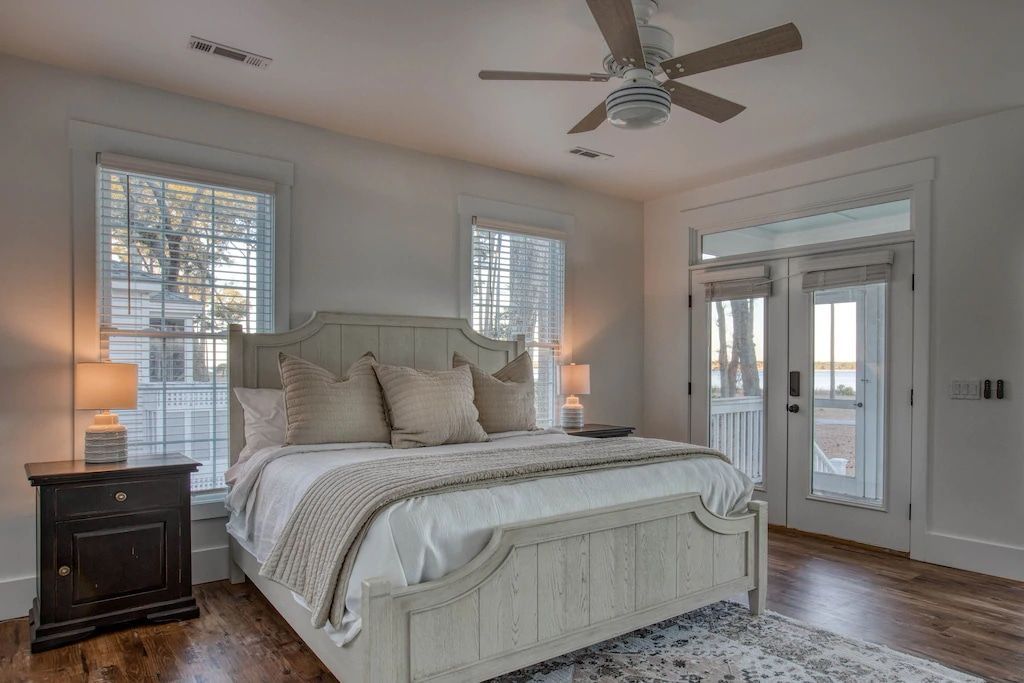 There is a large bed in the middle of the room with a ceiling fan.
