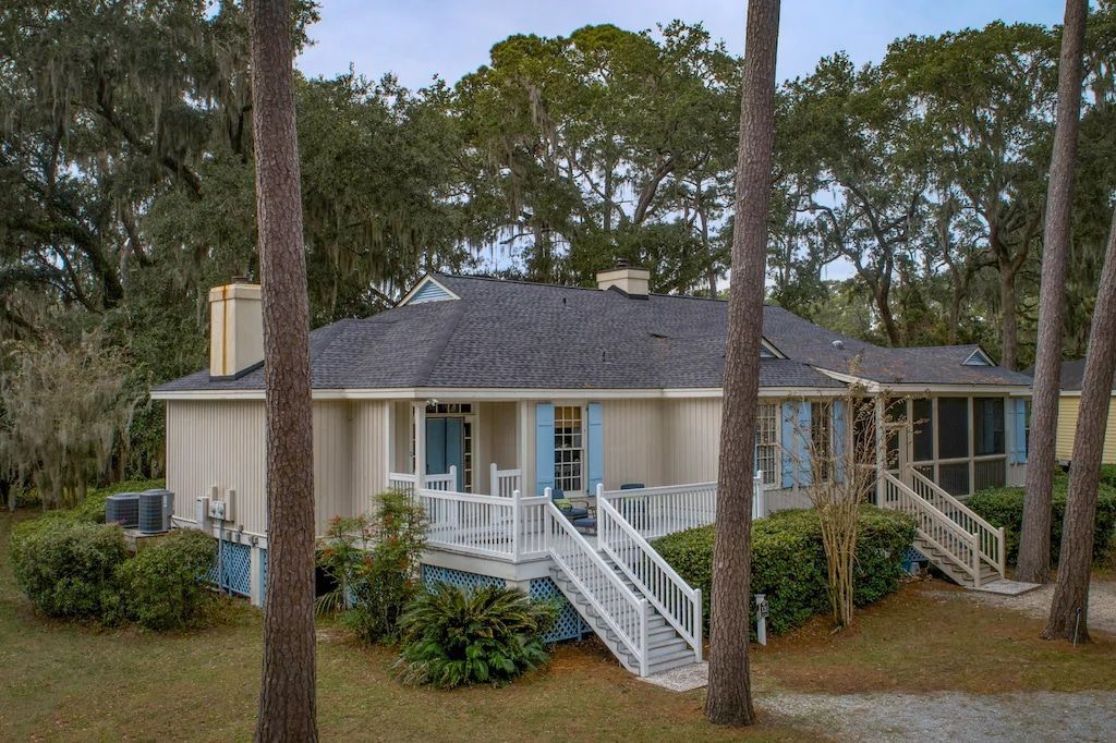 A house with a porch and stairs is surrounded by trees.