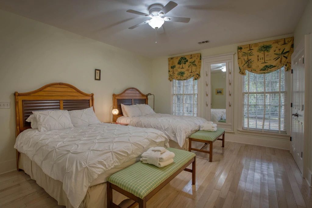 A bedroom with two beds and a ceiling fan.