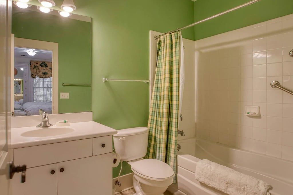 A bathroom with green walls , a toilet , sink , and bathtub.