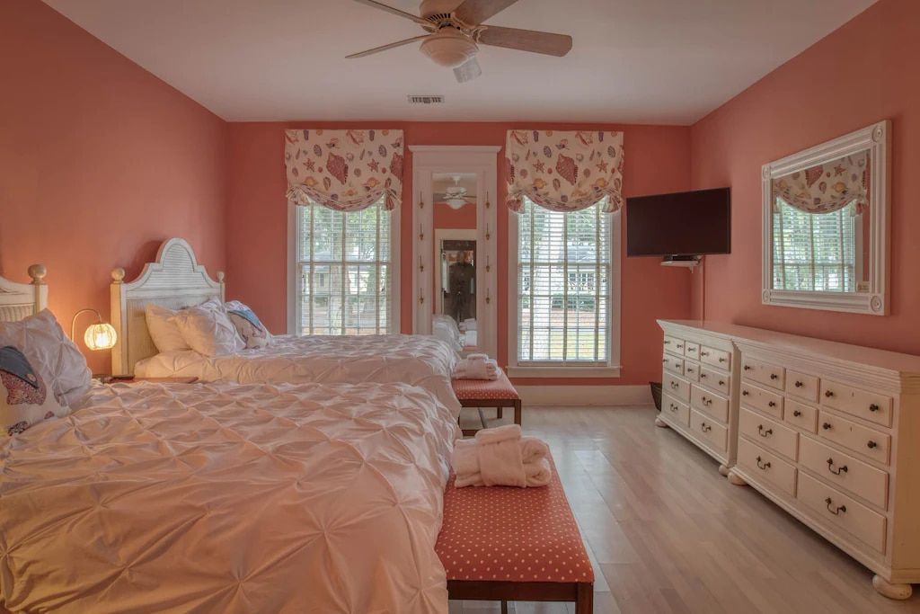 A bedroom with two beds , a dresser , and a television.