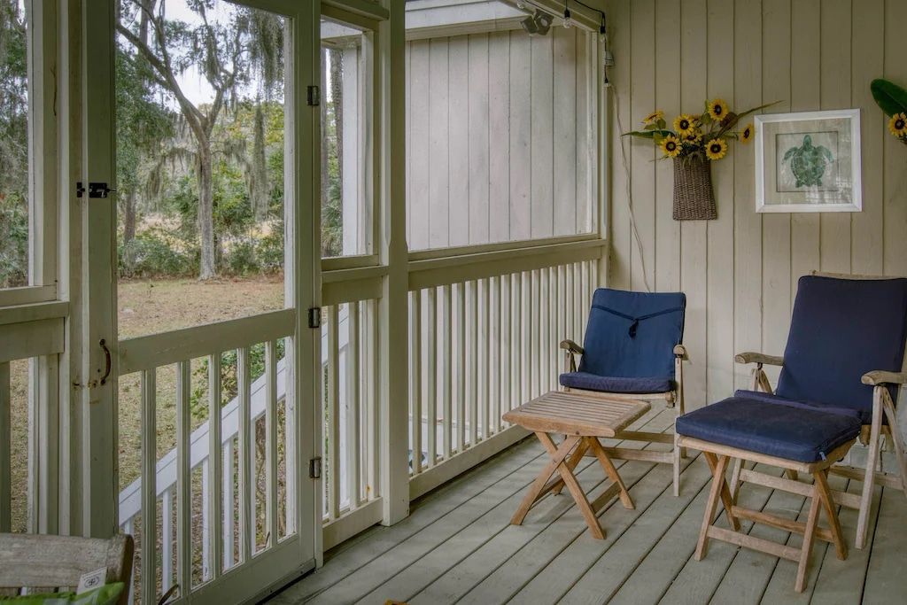 A screened in porch with chairs and a table
