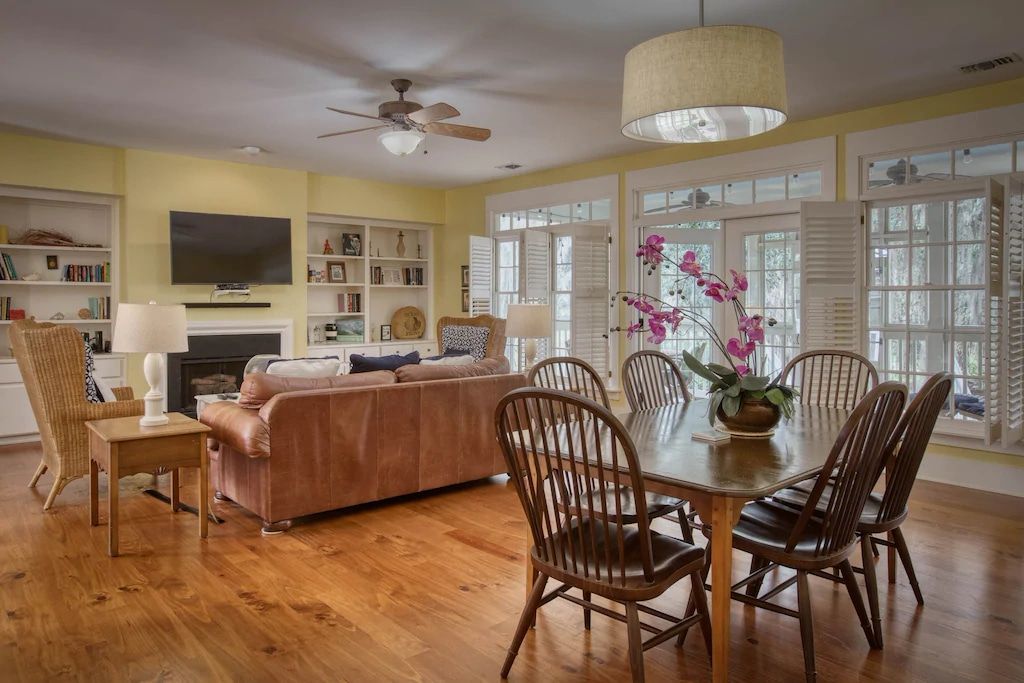 A living room with a dining table and chairs and a ceiling fan.