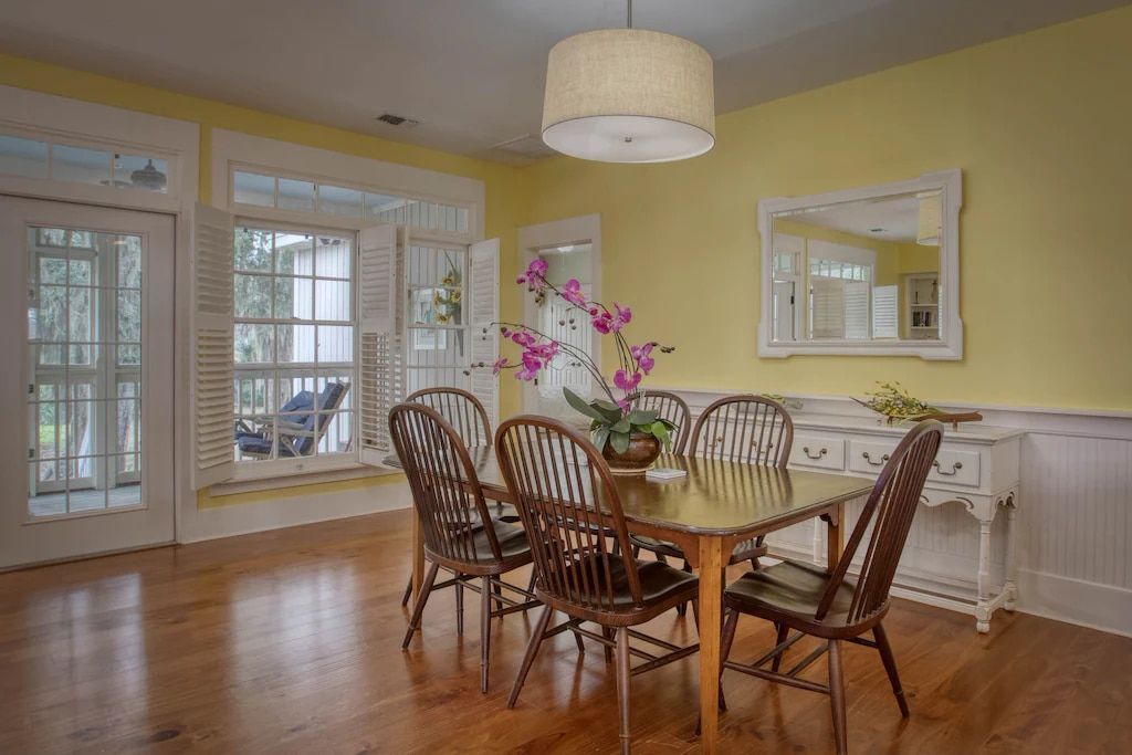 A dining room with a table and chairs and a mirror.