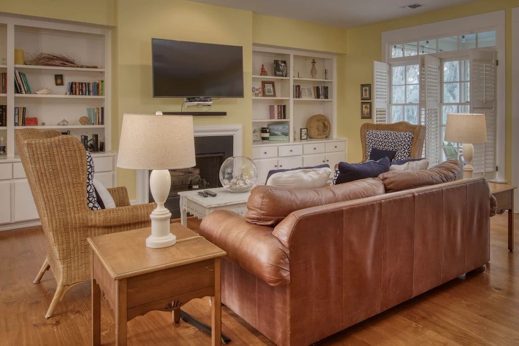 A living room with a couch , chairs , lamps and a flat screen tv.